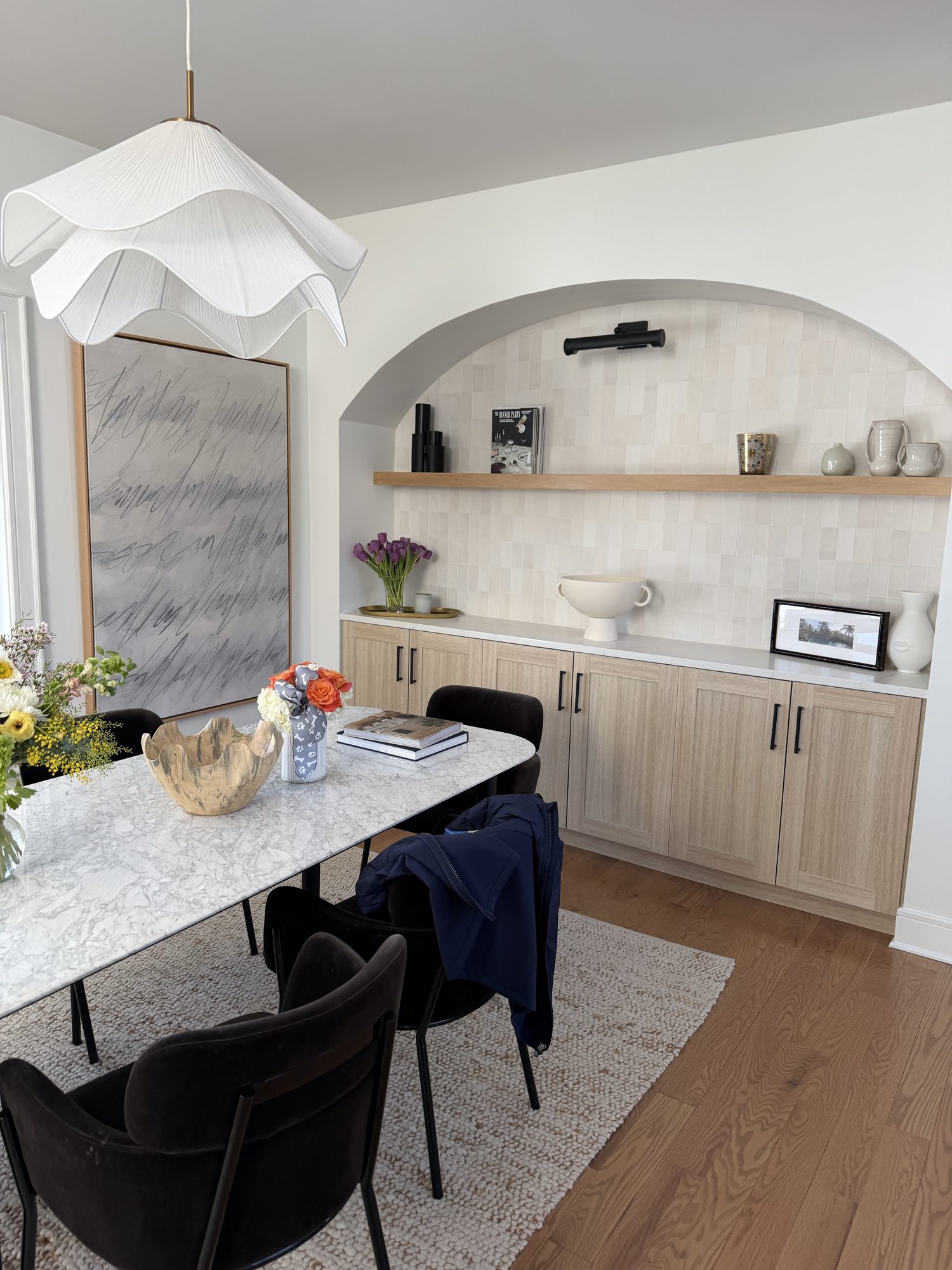 Full dining room with arched built-in, sculptural pendant, and marble table